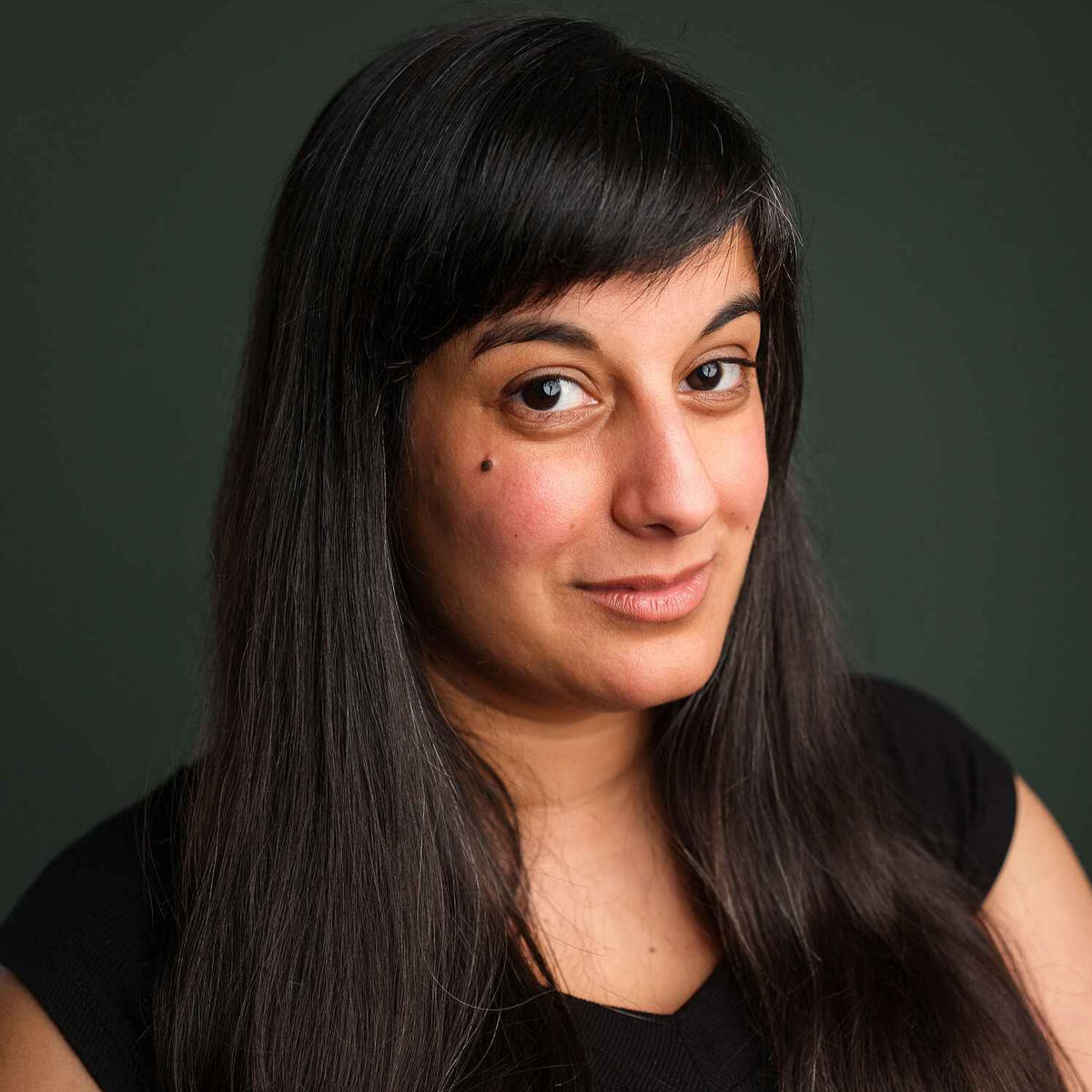 Michelle headshot Michelle, a mixed-race woman with long straight black hair, smiling against a dark green background
